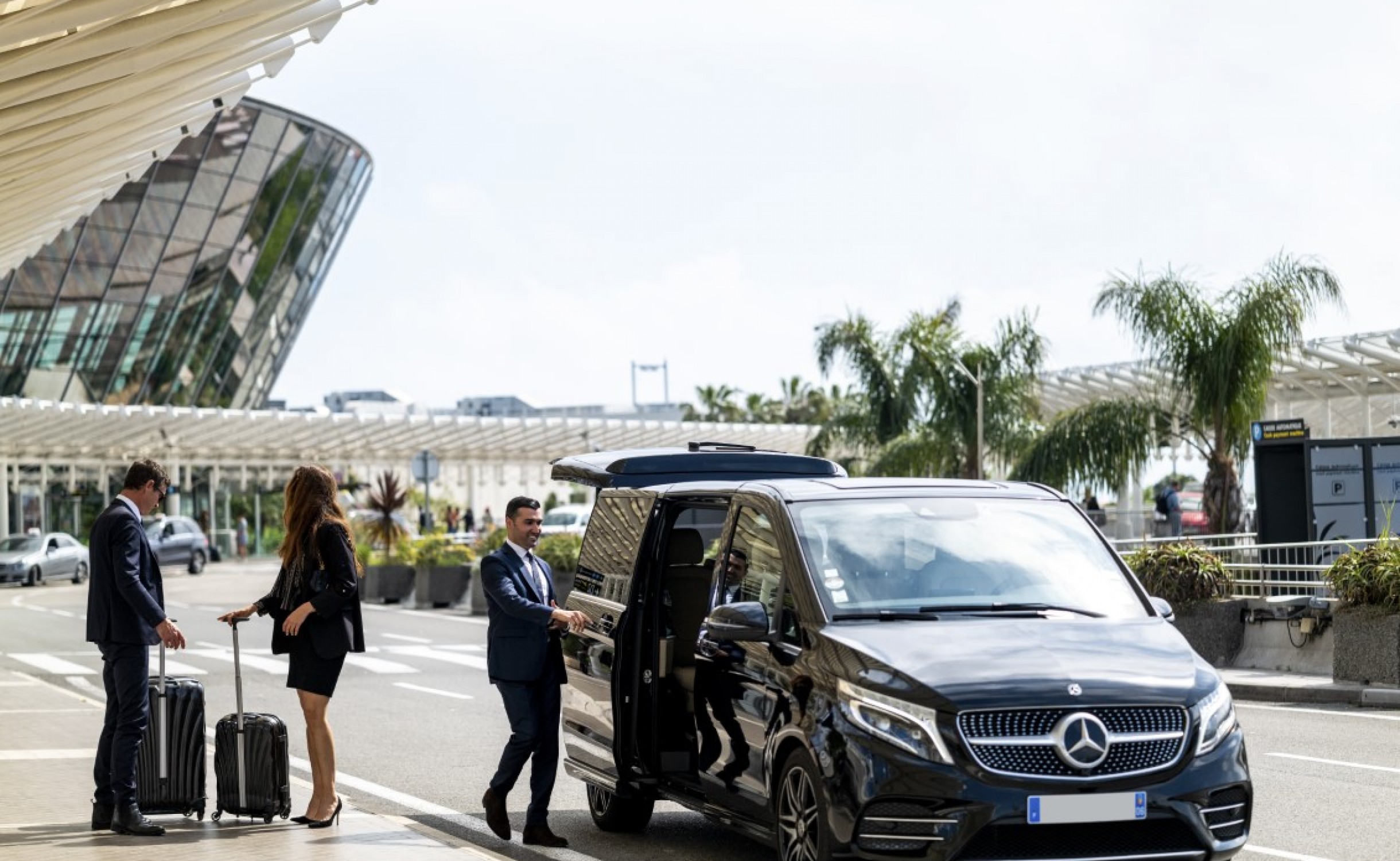 Couple having their luggage loaded into a airport shuttle.